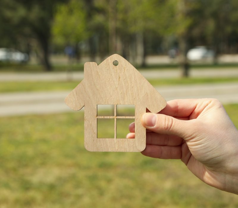Female hand holds wooden house. Buying a property